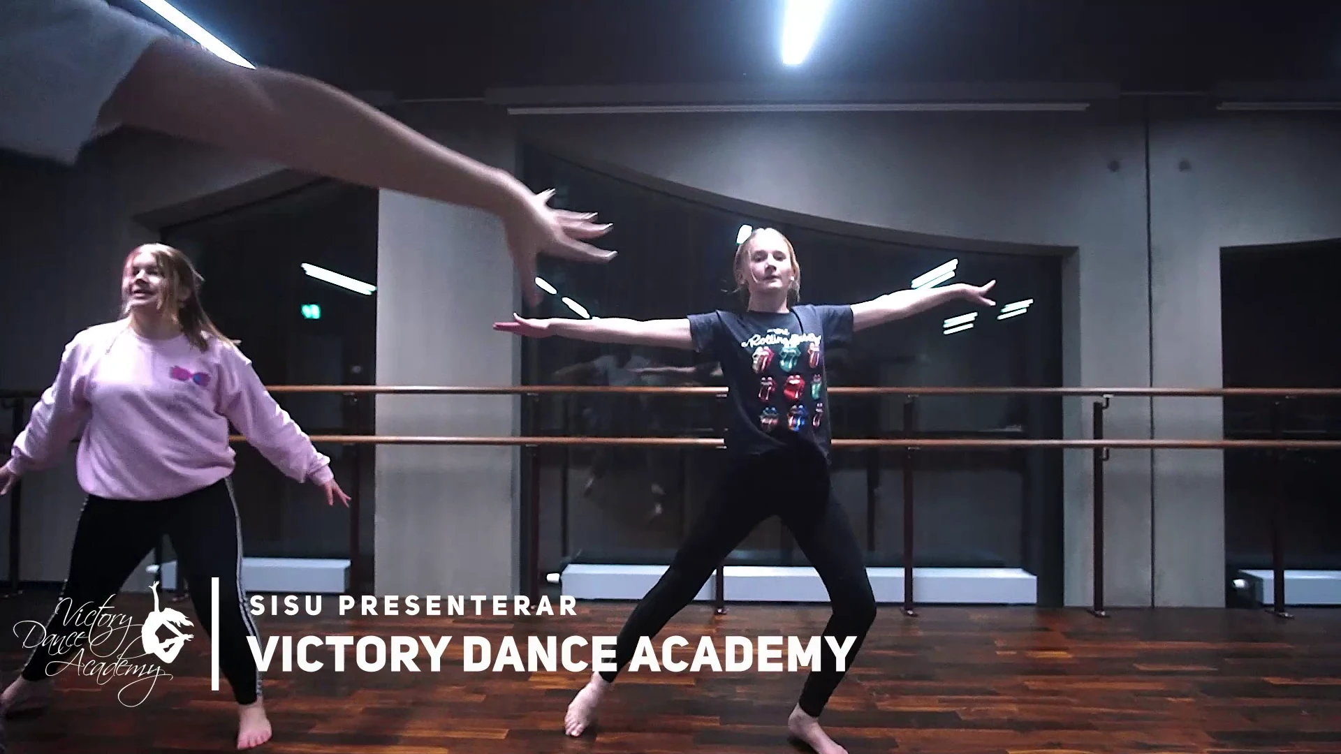 Unga dansare med utsträckta armar i en danssal, med texten ”SISU presenterar Victory Dance Academy” och skolans logotyp.