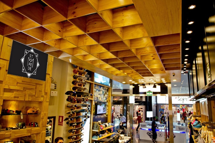 A shop with a wooden ceiling and skateboards on the wall, where a black sign with the logo in white hangs at the top left.